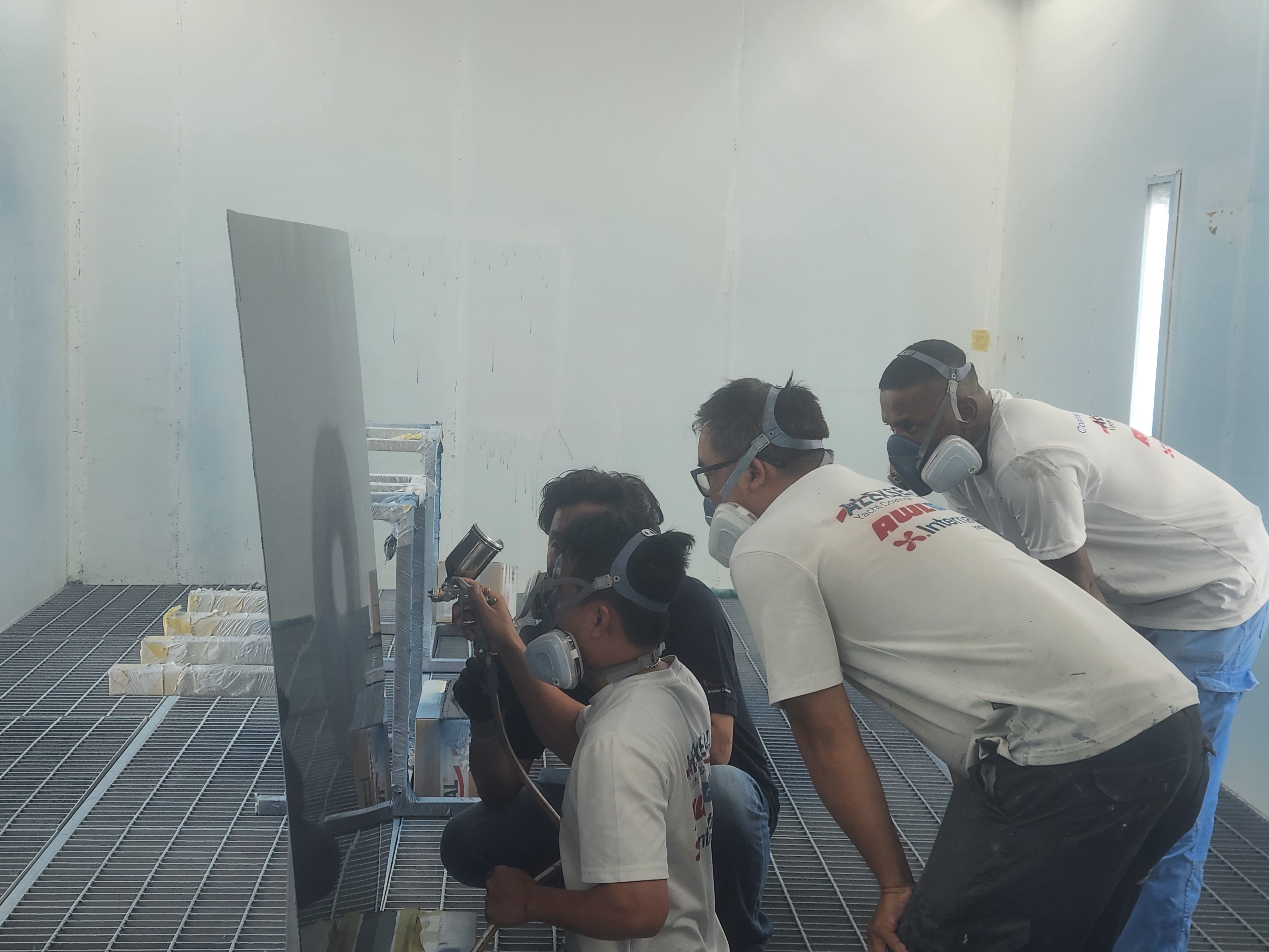ICS team practicing spray painting techniques in a professional booth