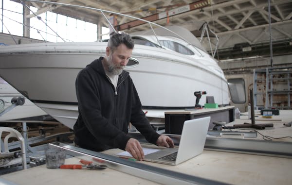 Skilled yacht technician working on boat coating in workshop